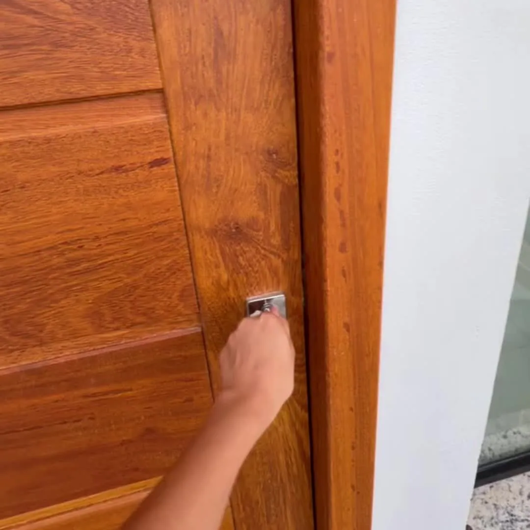 Mão abrindo a porta de madeira de uma casa.