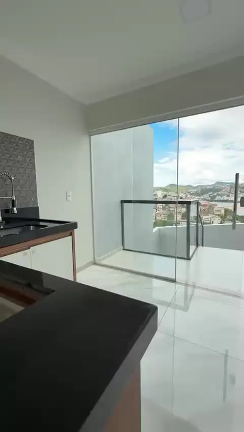 Cozinha integrada a uma varanda com guarda-corpo de vidro e vista para a cidade.